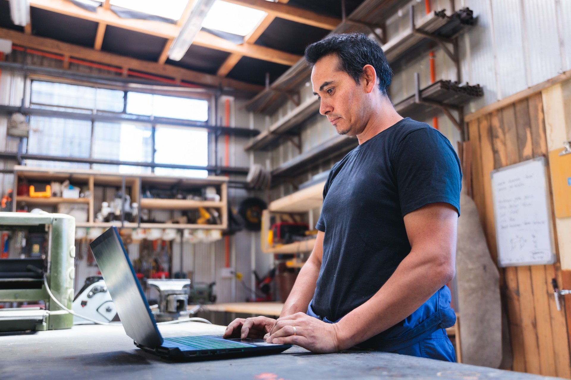 Carpenter and craftsman managing orders using laptop and talking on phone in workshop