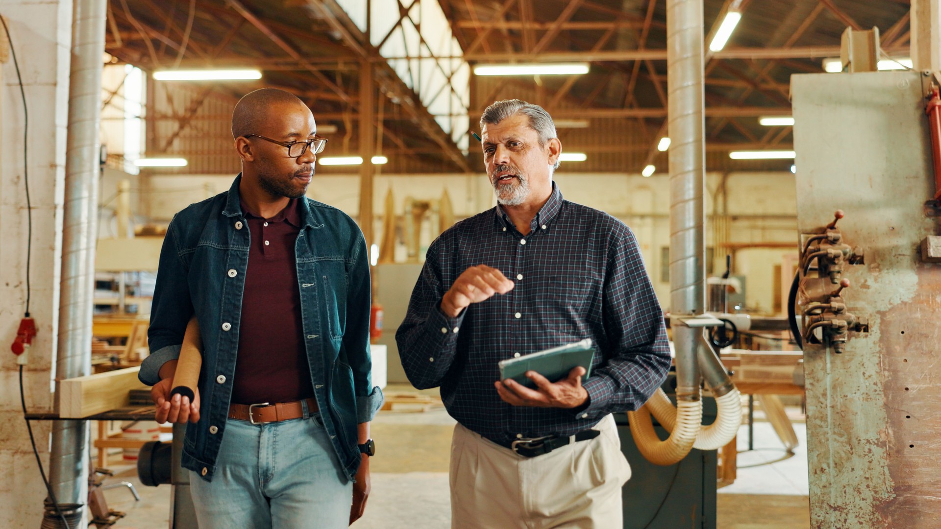 Talking, carpenter or people on tablet in workshop for factory, check inventory and furniture manufacturing. Woodworking, carpentry and online update for timber, lumber and construction business